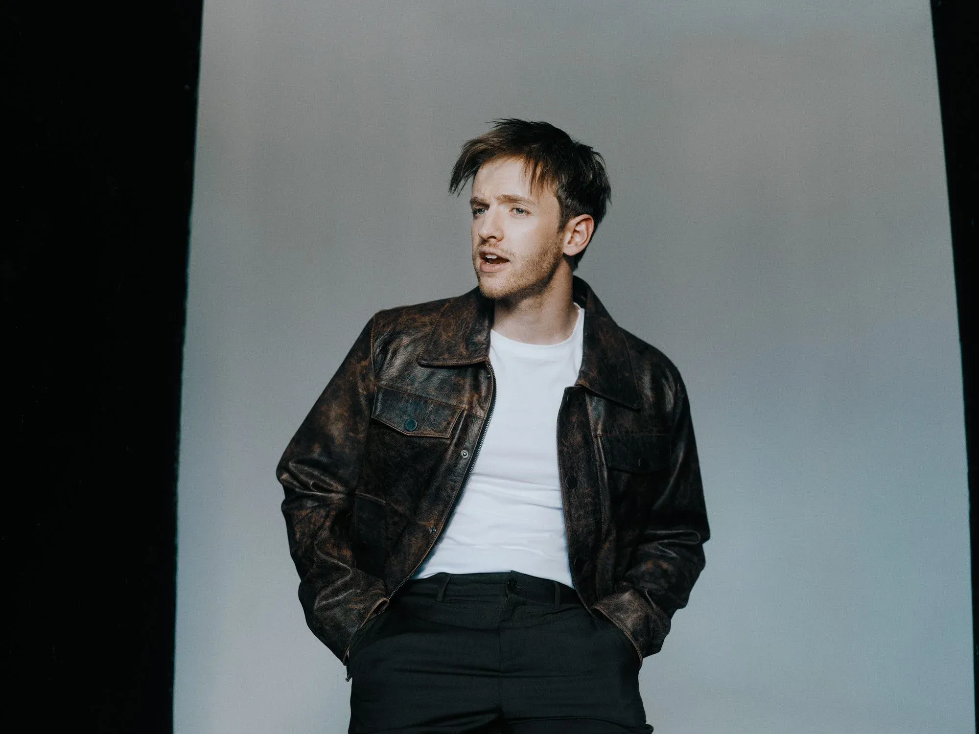Timur Bartels in Lederjacke vor grauem Hintergrund